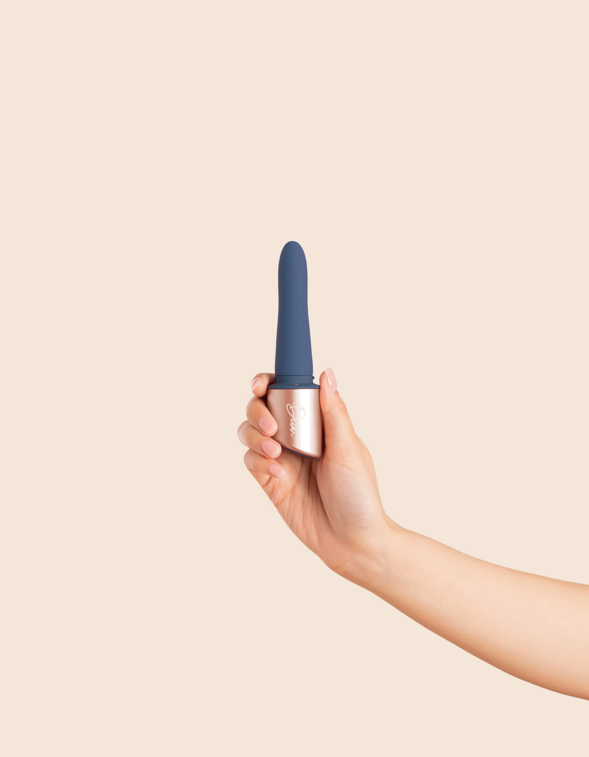 A hand holds a blue and rose gold dual motor vibrator.