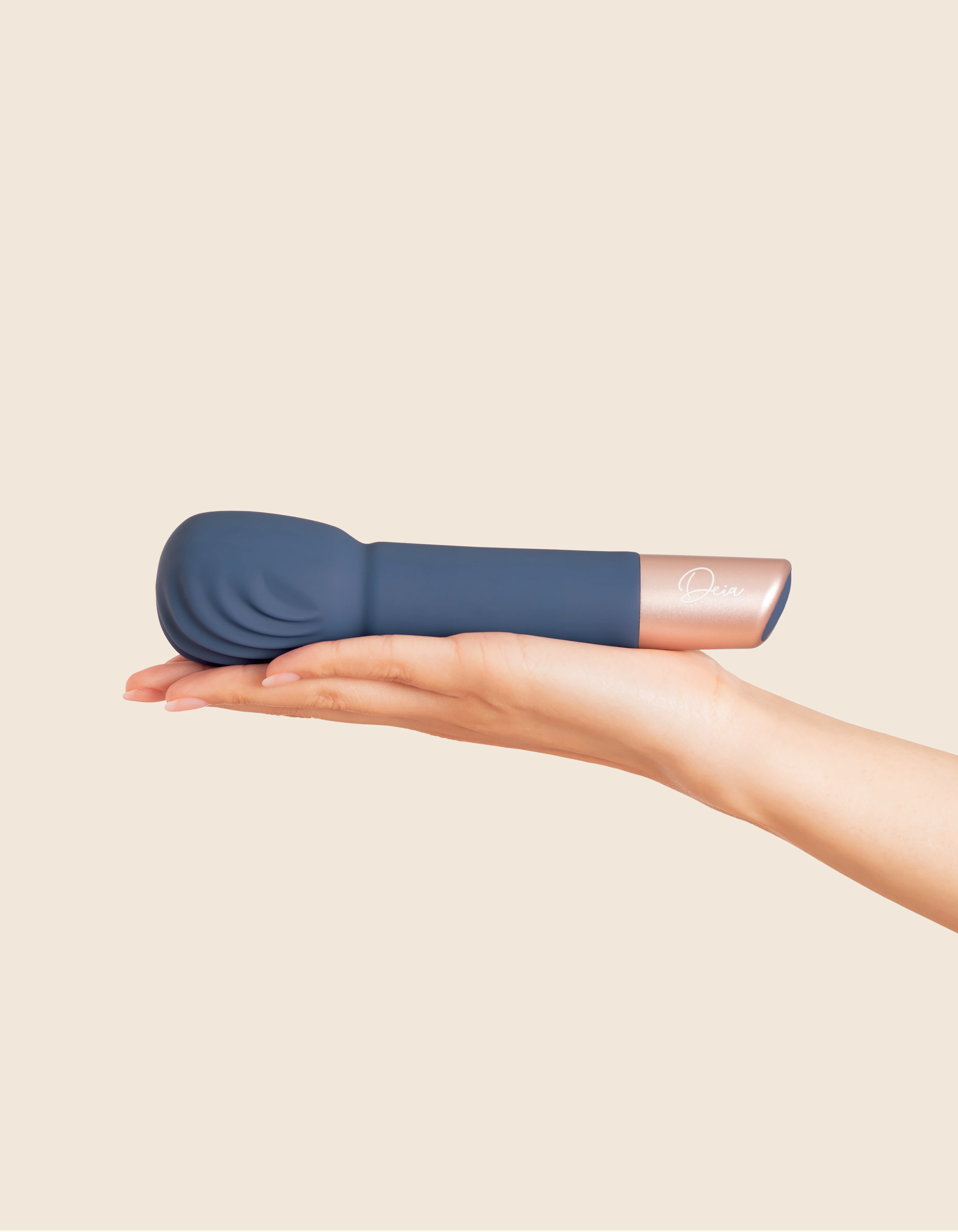 A blue silicone massage wand with rose gold accents rests on a hand.