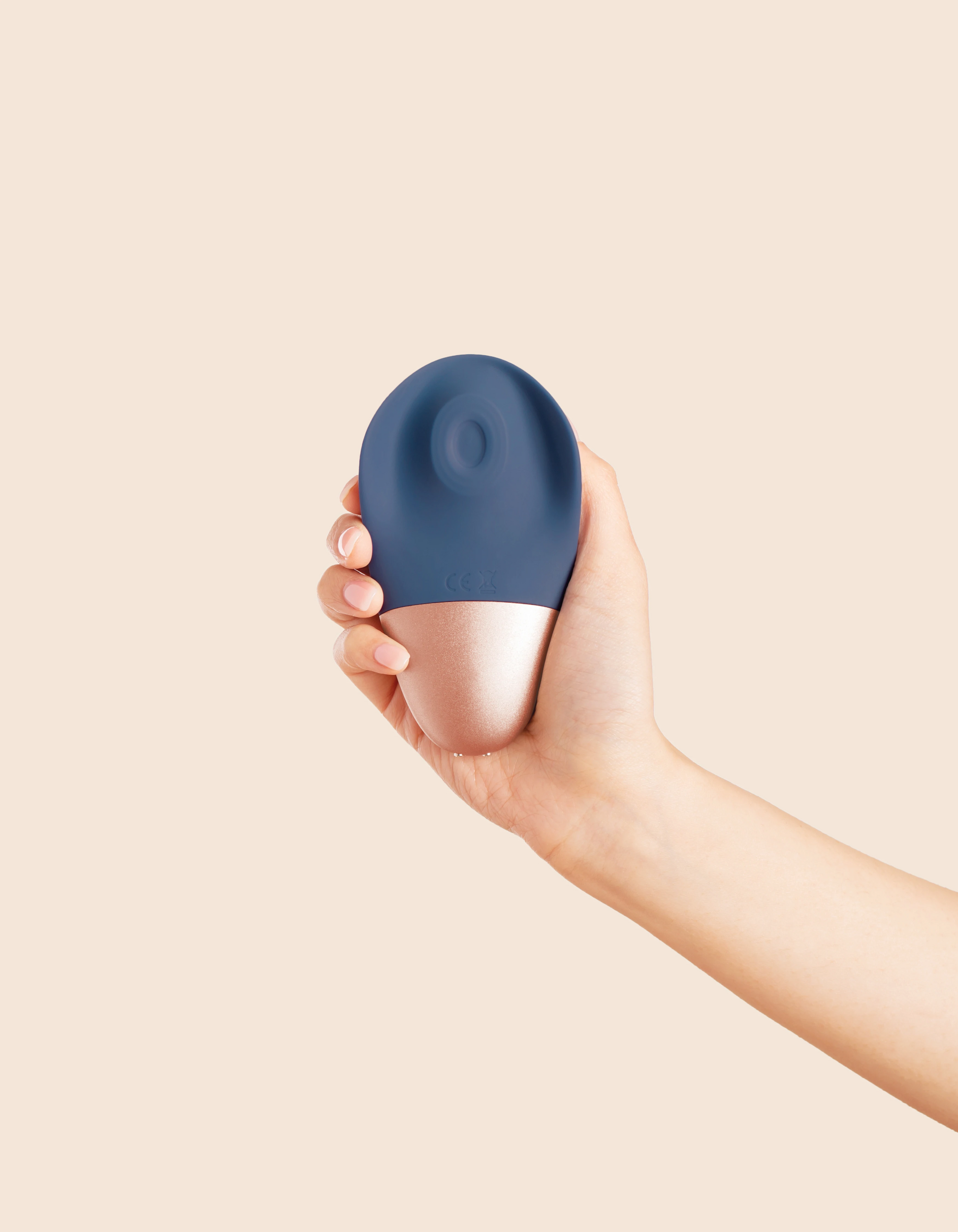 A hand holds a blue and rose gold rechargeable wand massager.