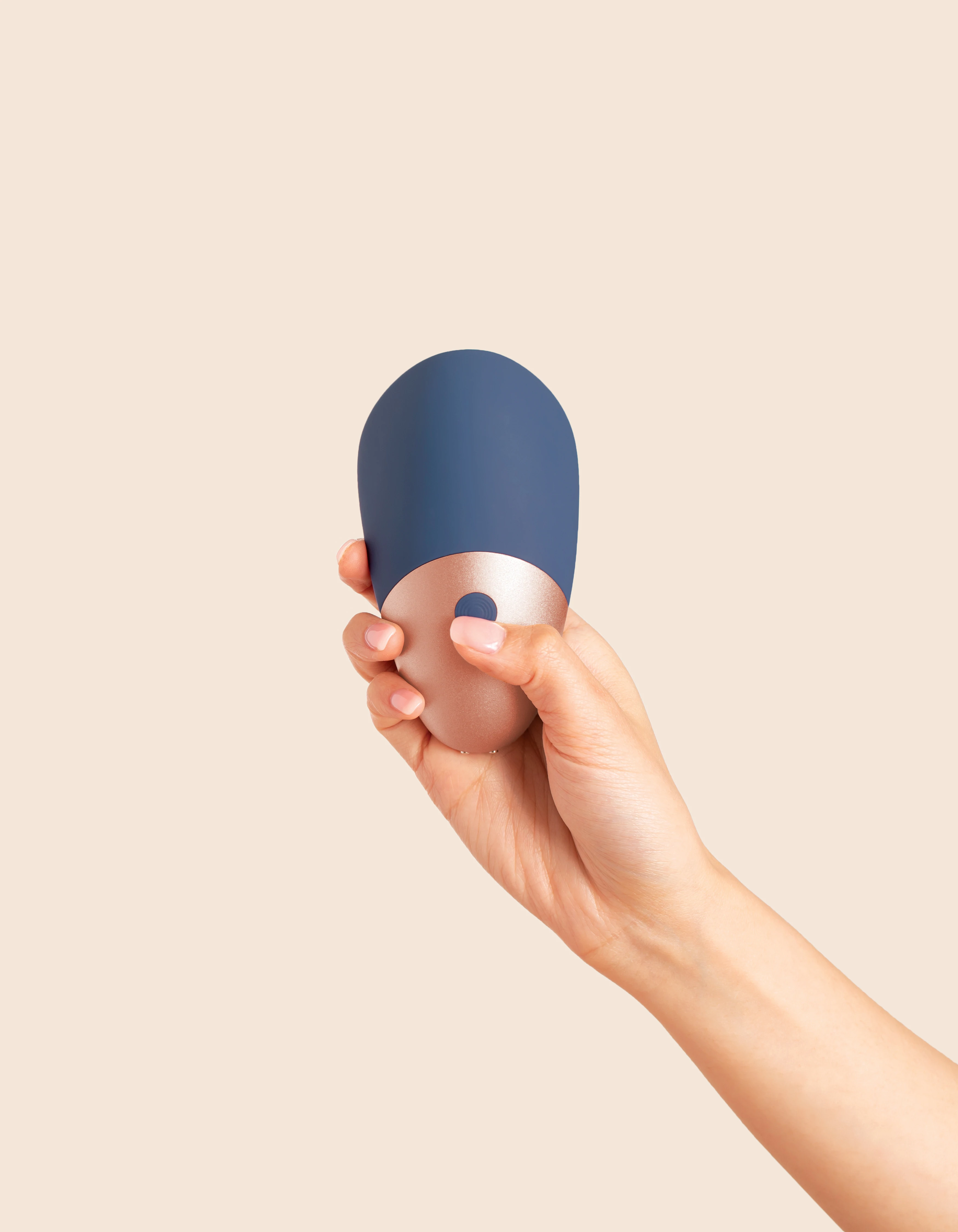 A hand holds a blue and rose gold rechargeable wand massager.