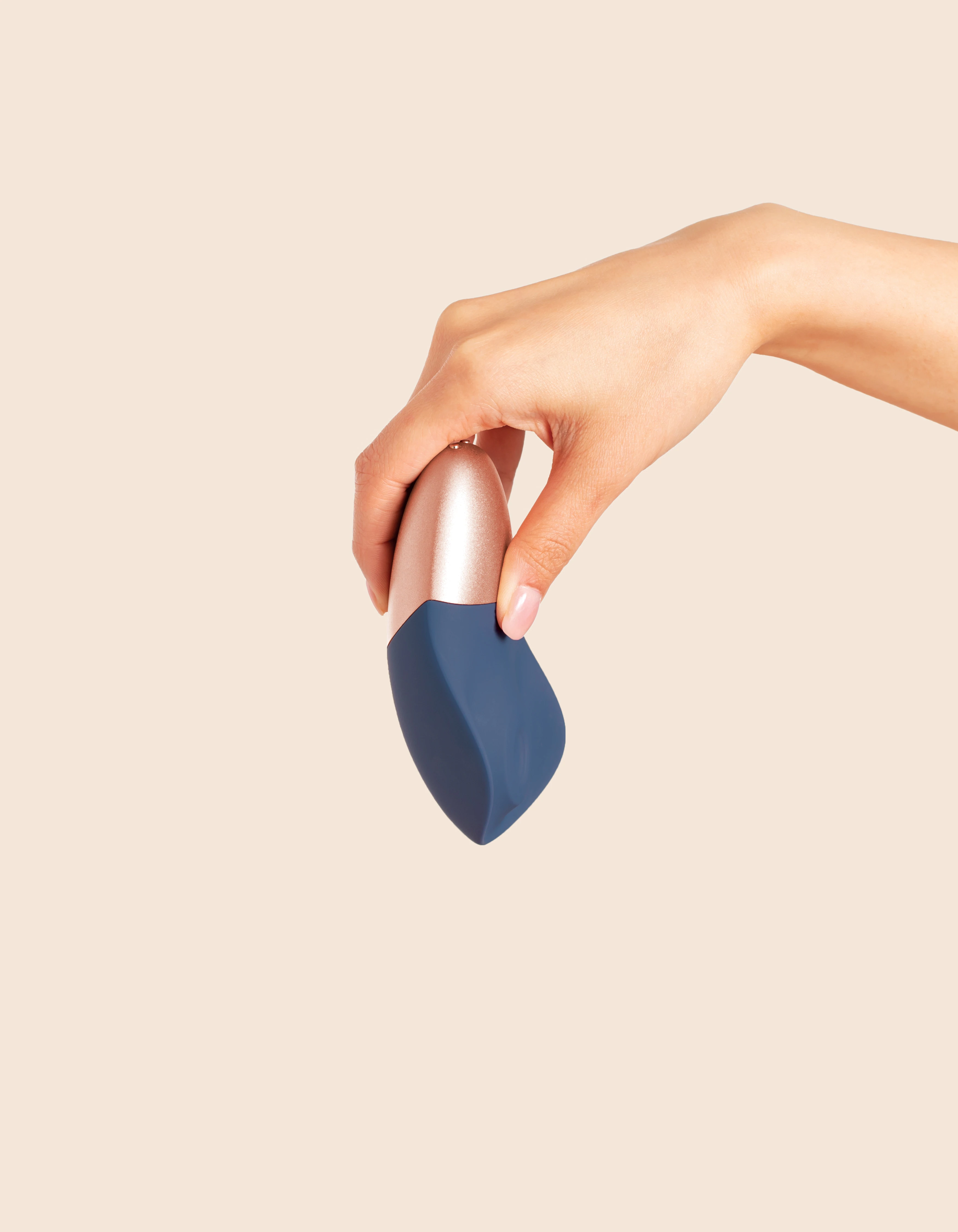 A hand holds a blue and rose gold rechargeable wand massager.