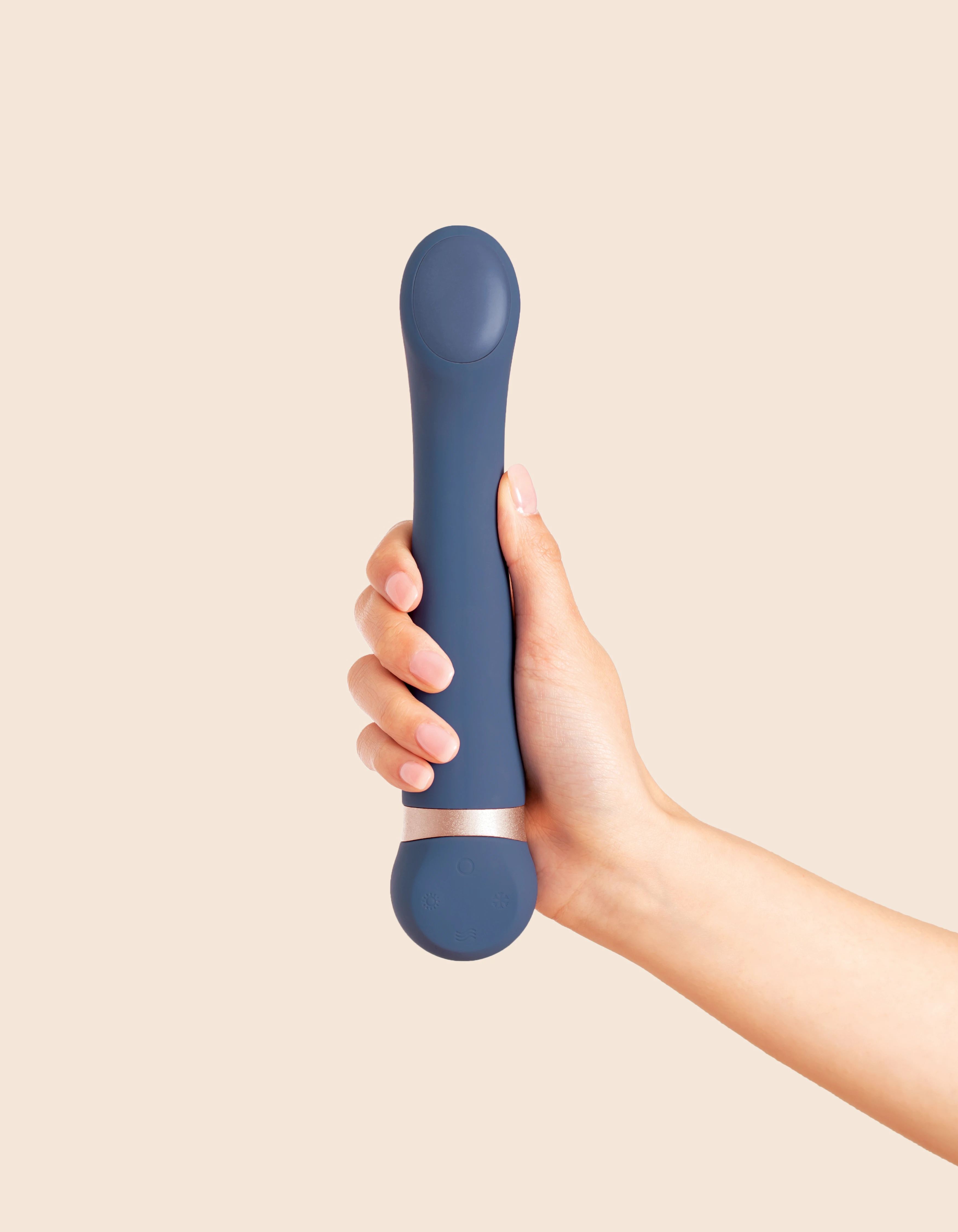 A hand holds a blue vibrating massager with a rose gold band.
