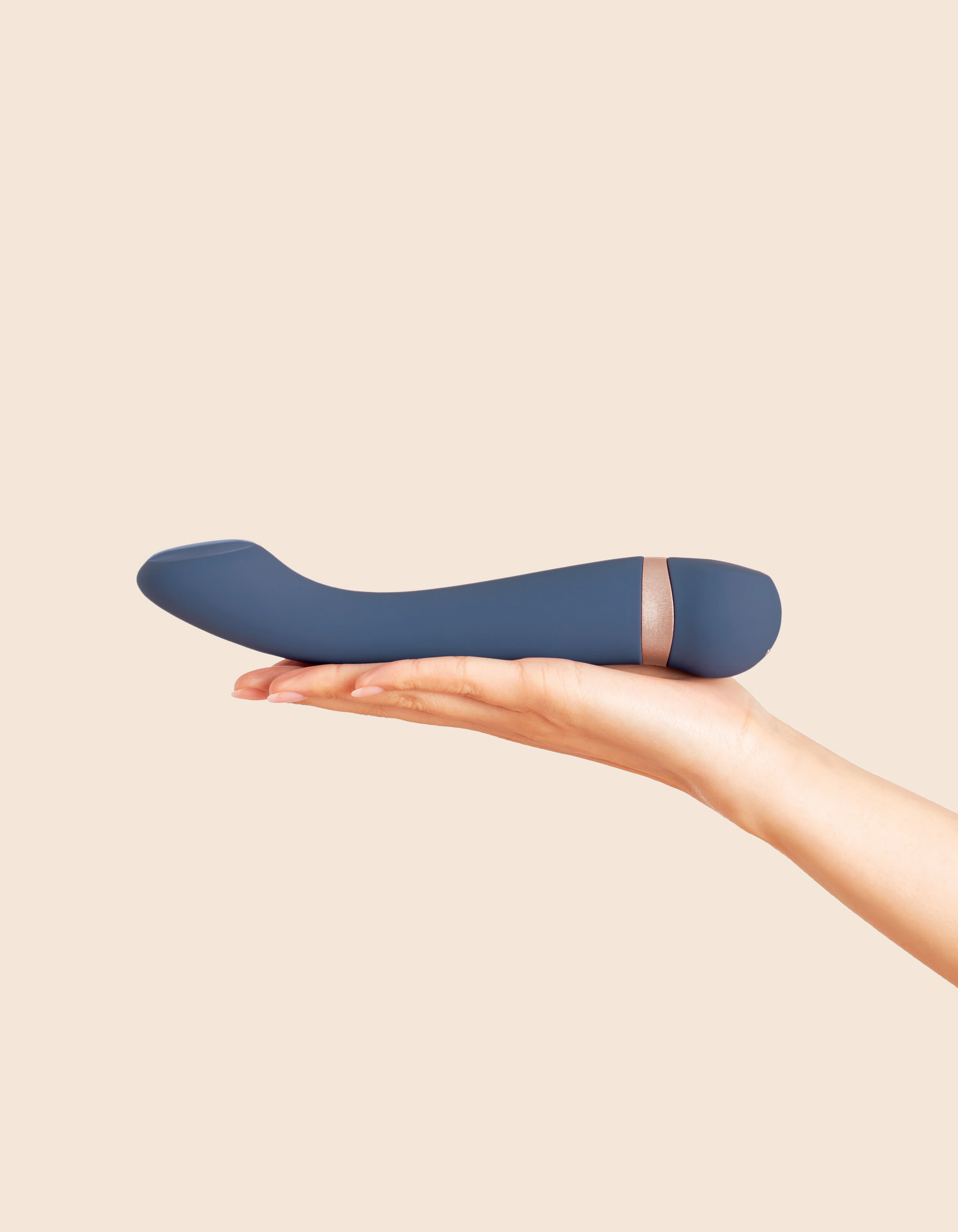 A blue vibrating massager with a rose gold band rests on an open palm.