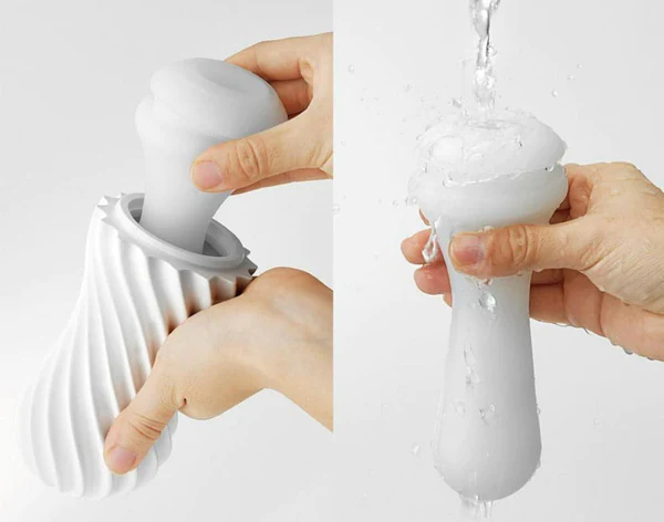 A white reusable masturbation sleeve being inserted into a textured white base and then rinsed with water.