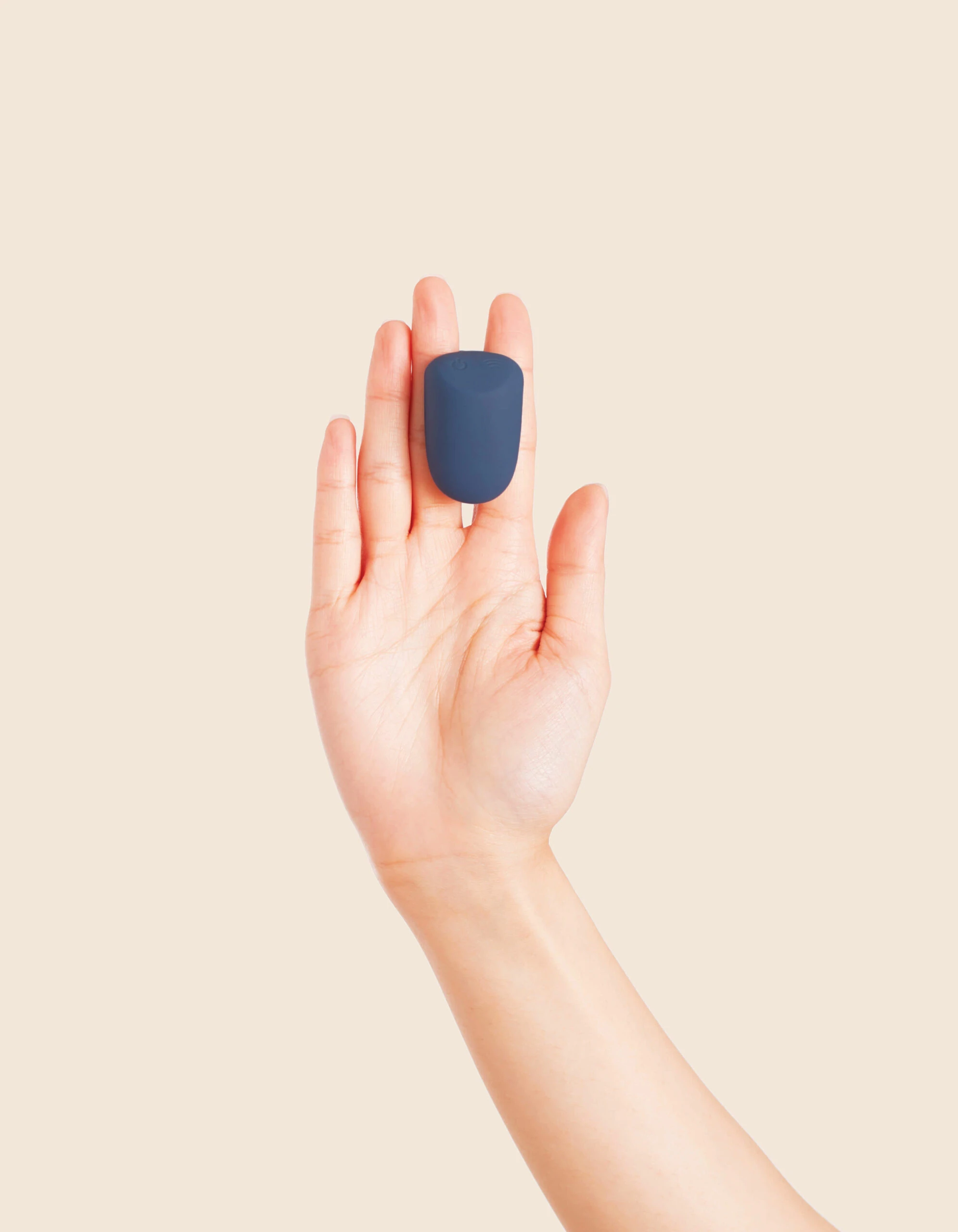 A blue wearable remote control vibrator rests on an open palm.