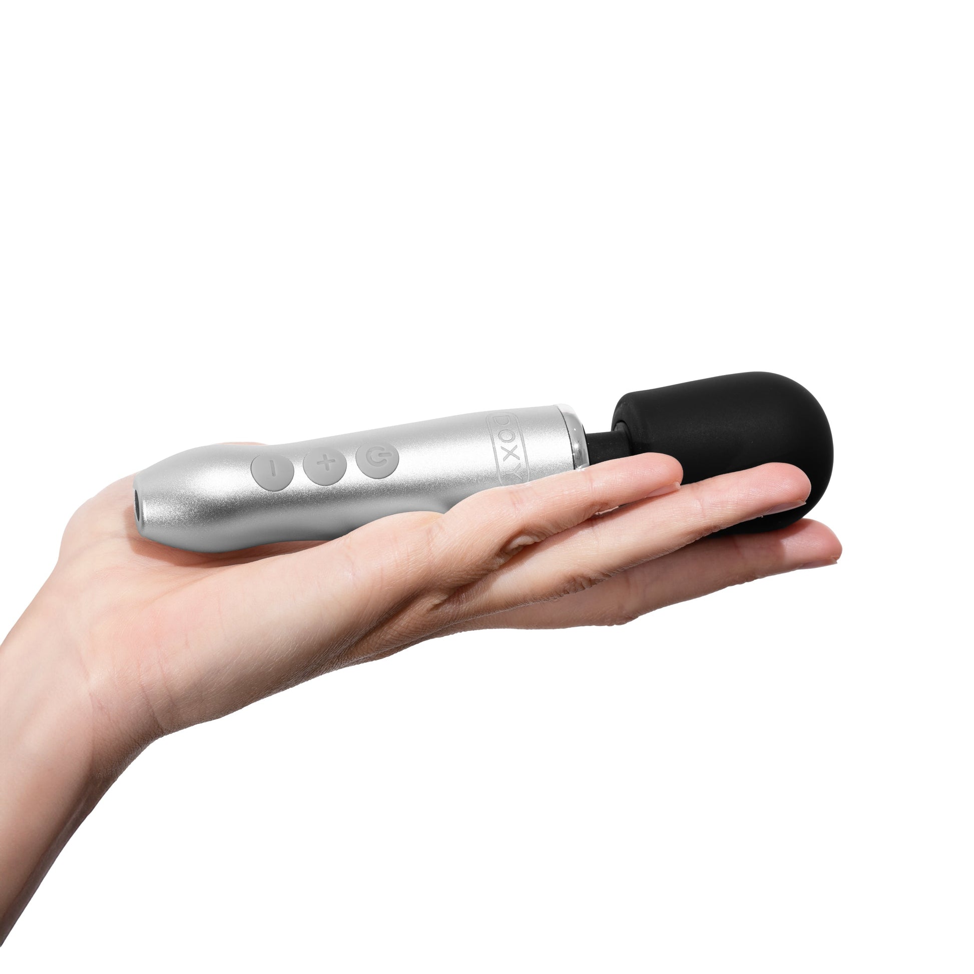 A silver compact wand massager with a black head rests in an open palm.