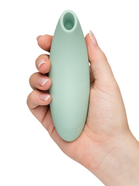 A sage green We-Vibe Melt 2 clitoral stimulator held in a hand.