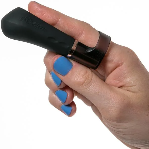 A black finger vibrator with a rose gold accent on a person's finger.