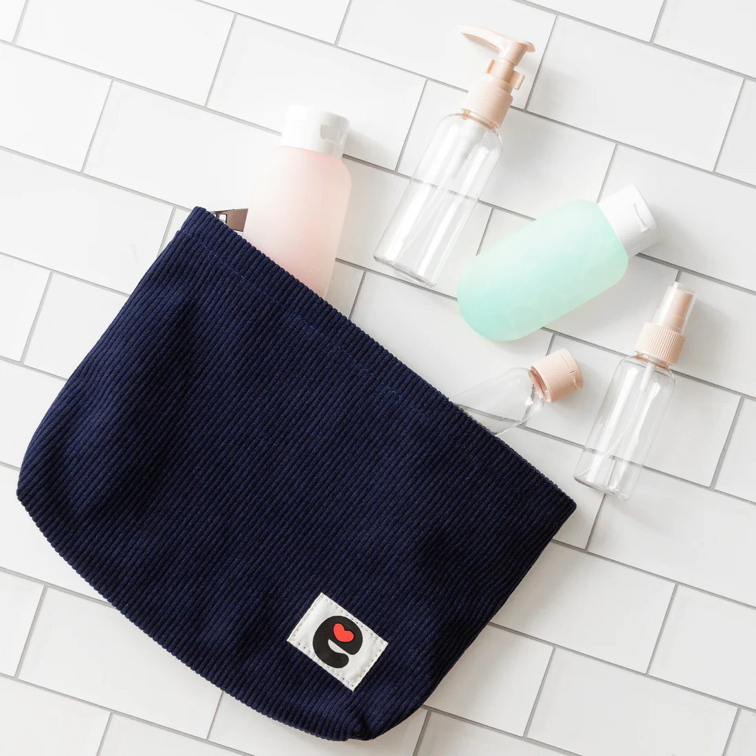 Midnight blue corduroy travel pouch with a white patch featuring a black "e" and red heart logo.