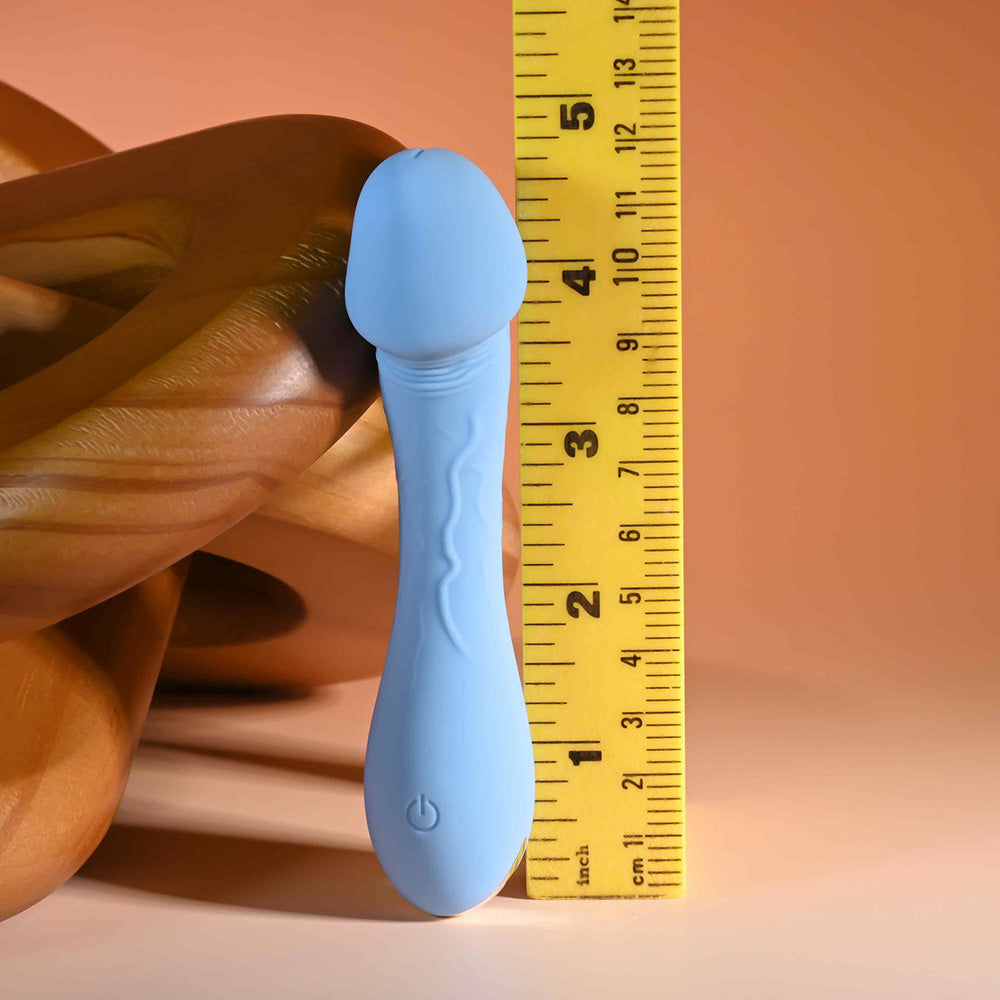 A light blue silicone vibrator with a curved head and a power button symbol, shown next to a ruler.