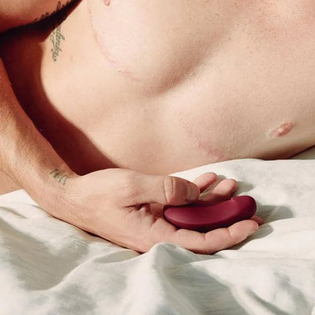 A plum-colored, flexible silicone vibrator held in a hand.