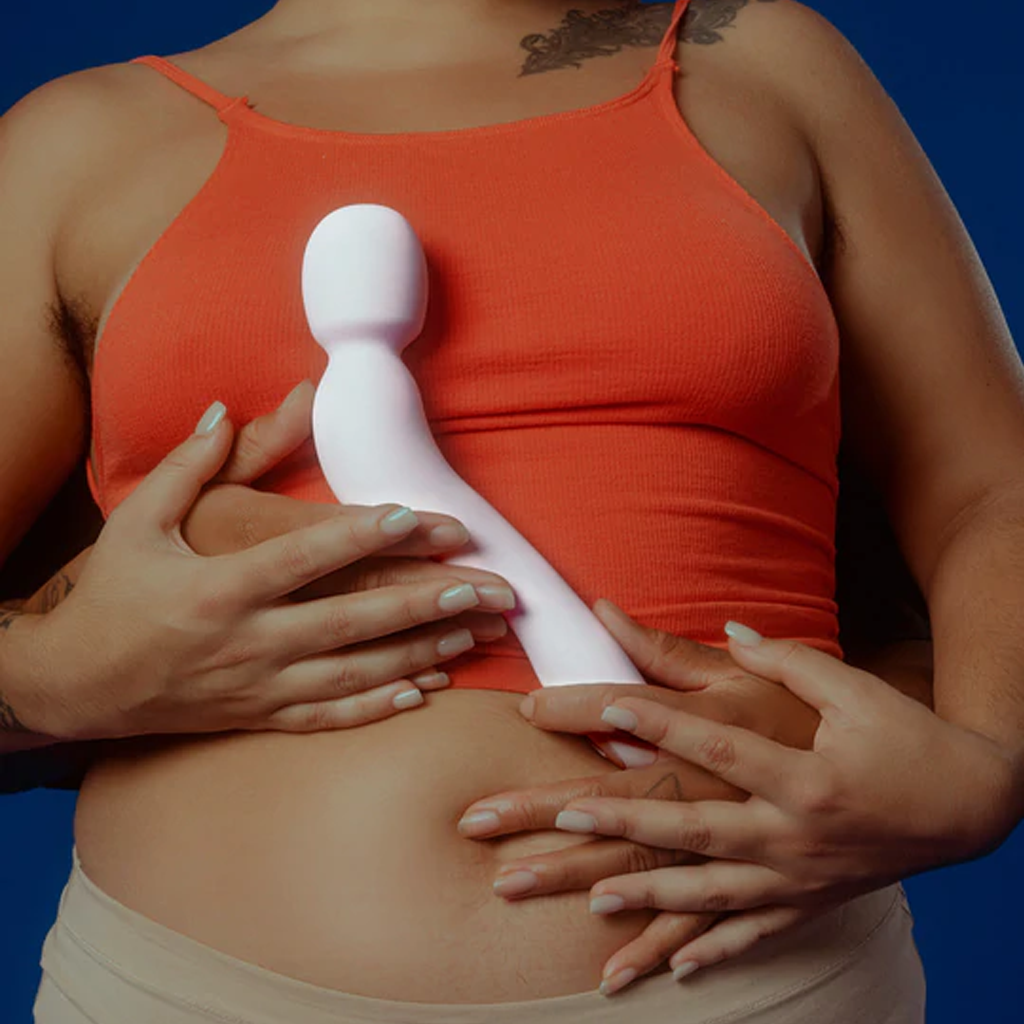 A pink wand vibrator held against a person's torso.