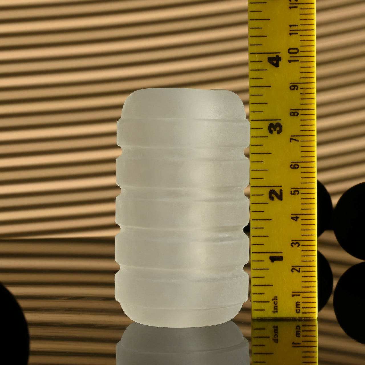 Frosted white TPE stroker with ribbed texture and a vibrating C-ring, measured against a ruler.