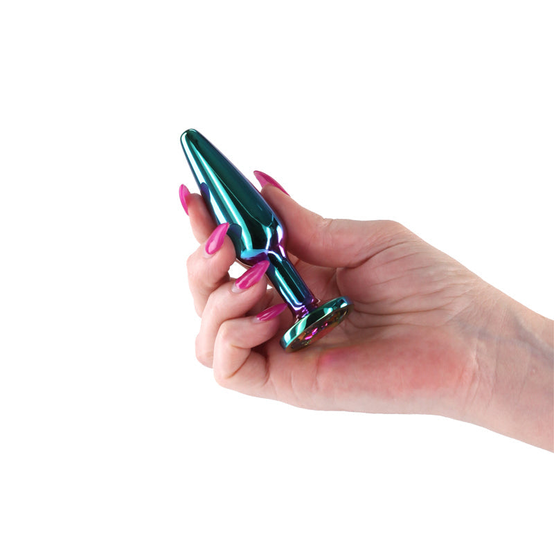A hand holds a tapered, rainbow-colored aluminum anal plug.