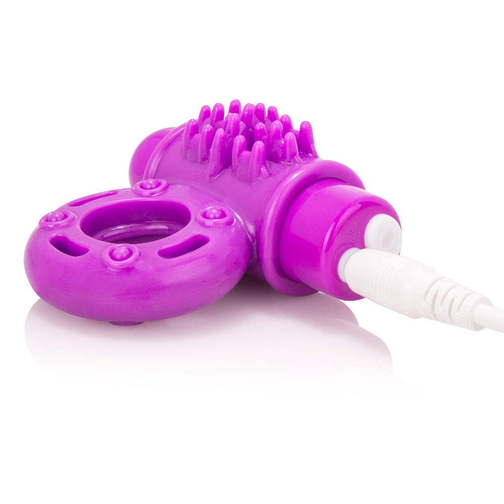 A purple vibrating cock ring with a textured surface and a white charging cable.