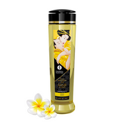 Shunga Serenity Monoi massage oil in a clear bottle with a black cap and a label featuring an illustration.