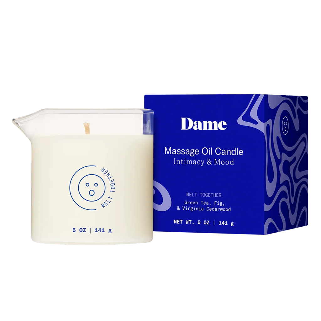 A white massage oil candle in a glass container with a blue box.