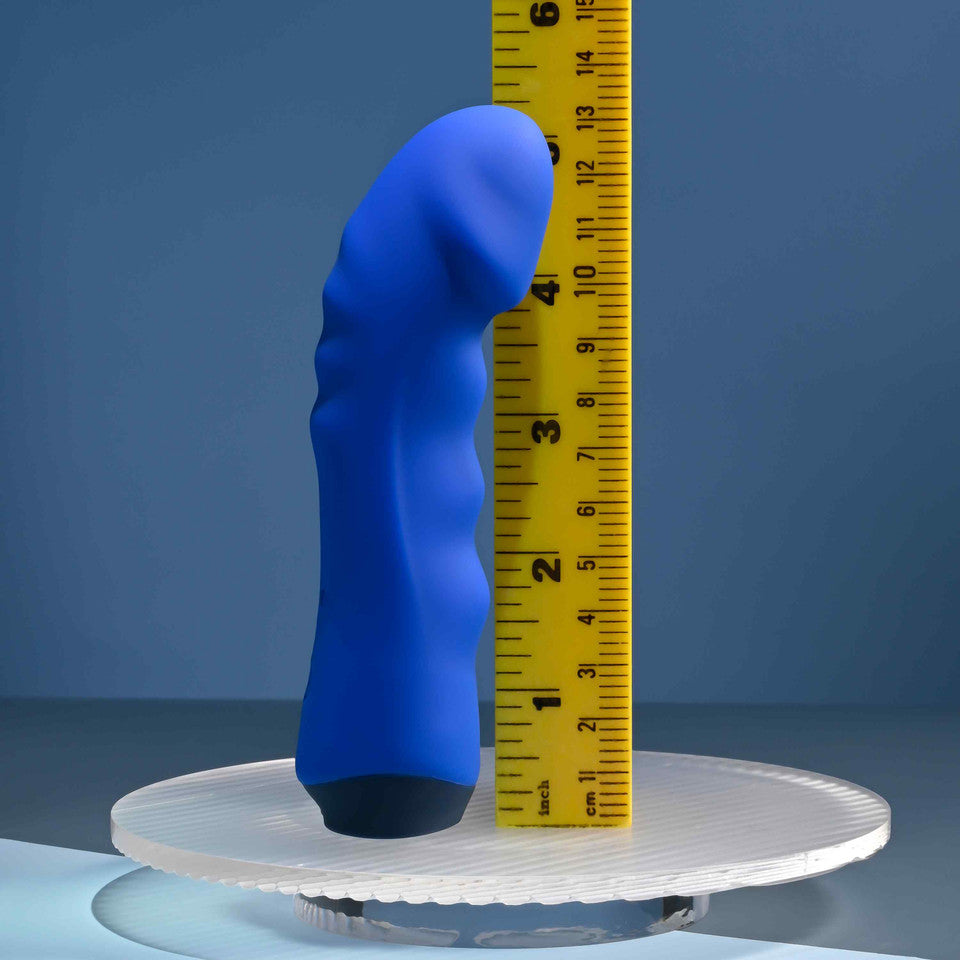 Blue silicone vibrator with wavy texture and curved head, measured against a ruler.