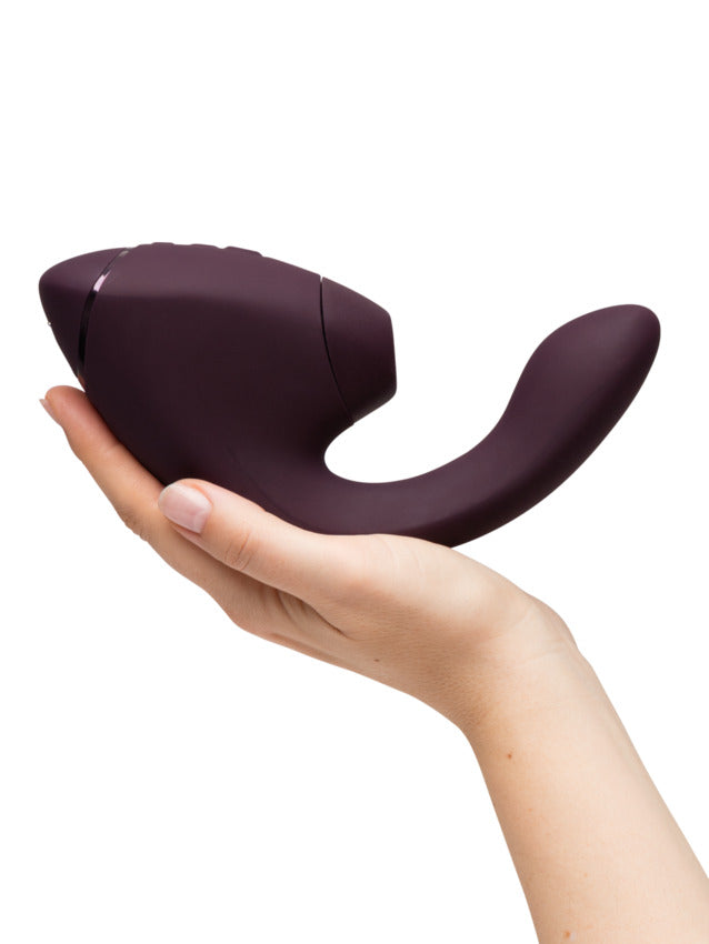 A purple dual clitoral and G-spot stimulator held in a hand.