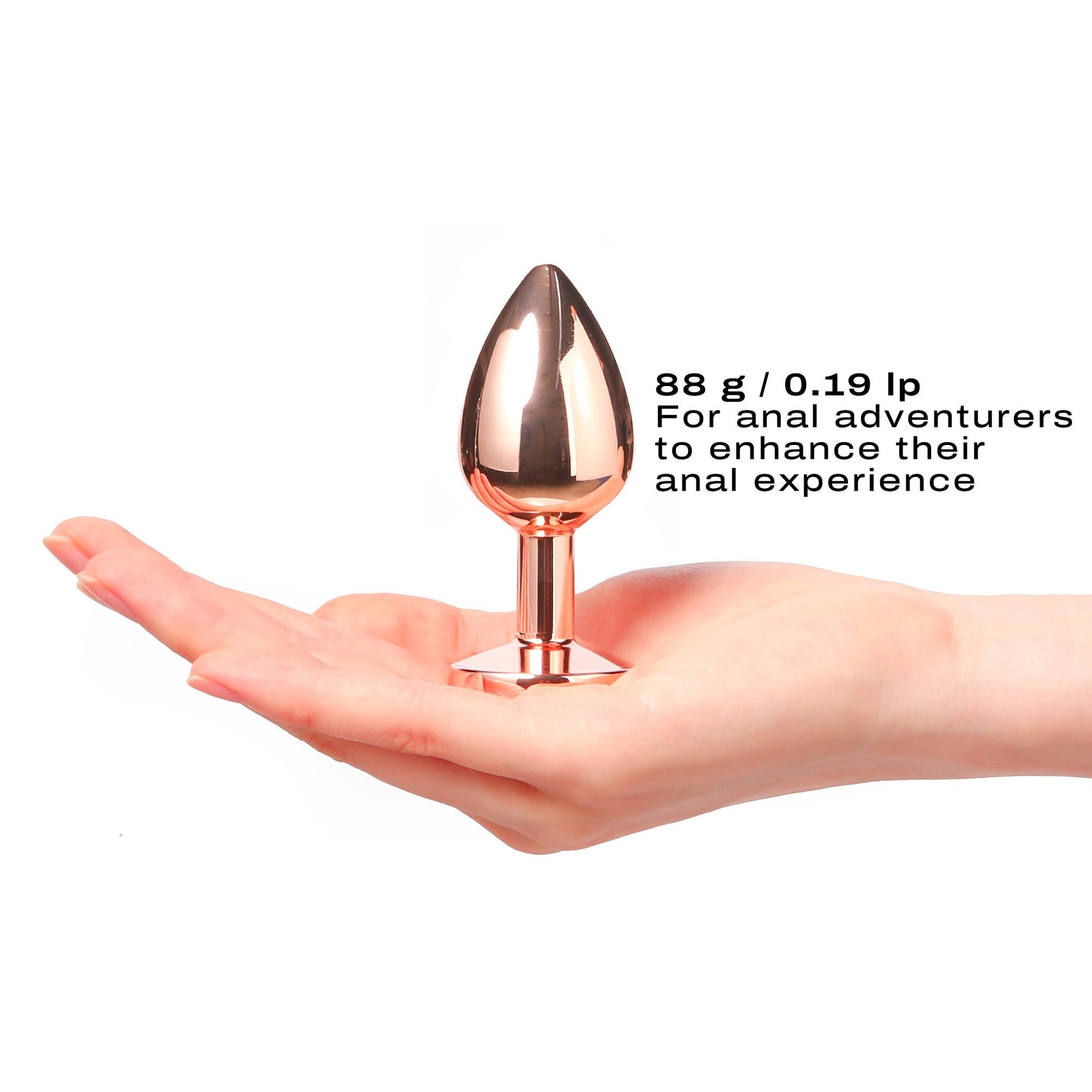 Rose gold metal anal plug with a diamond-shaped tip held in a hand.