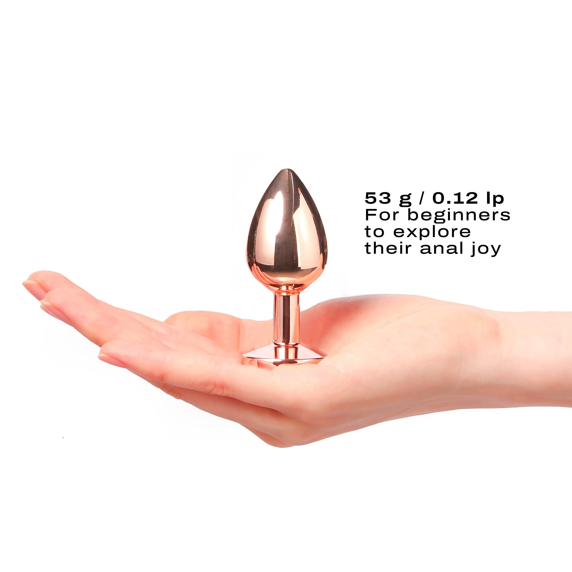 Rose gold metal anal plug with diamond base held in a hand.