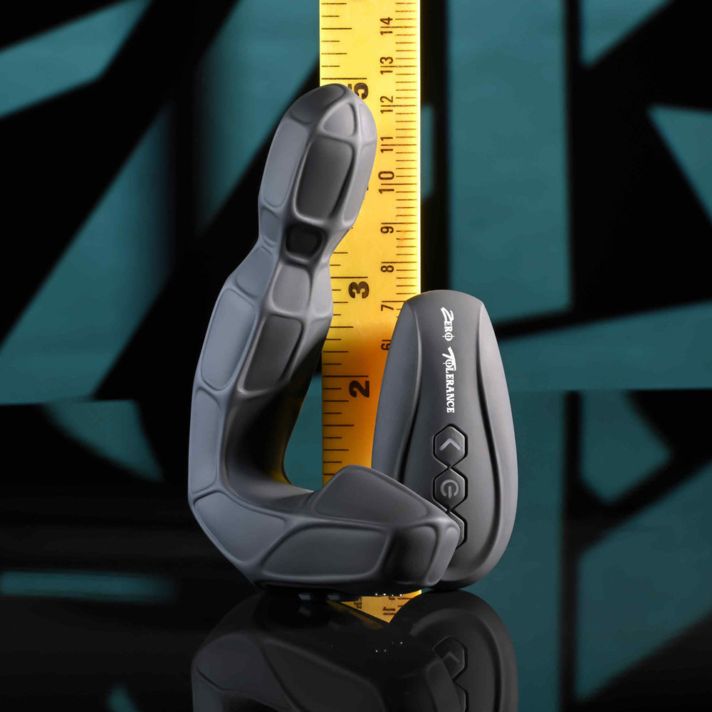 A black prostate massager with a twirling head and remote control is shown next to a ruler.