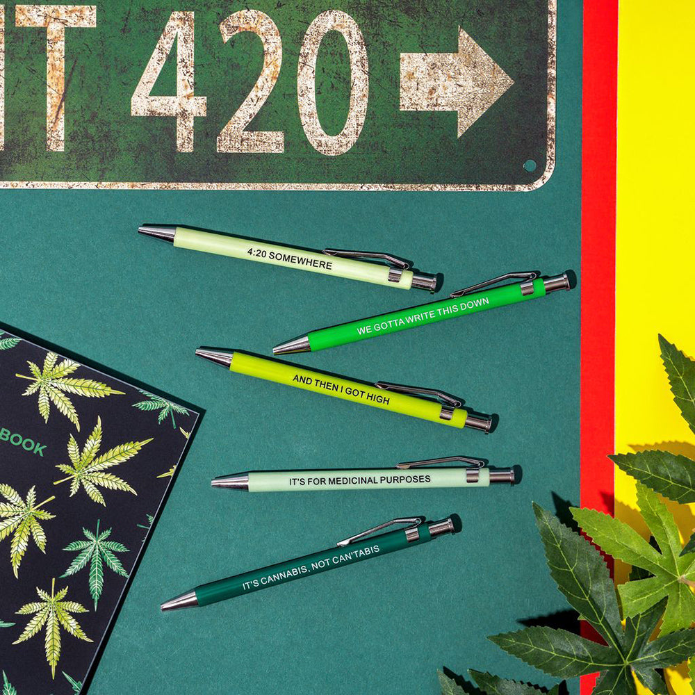Five novelty pens with cannabis-themed sayings on a dark green background.