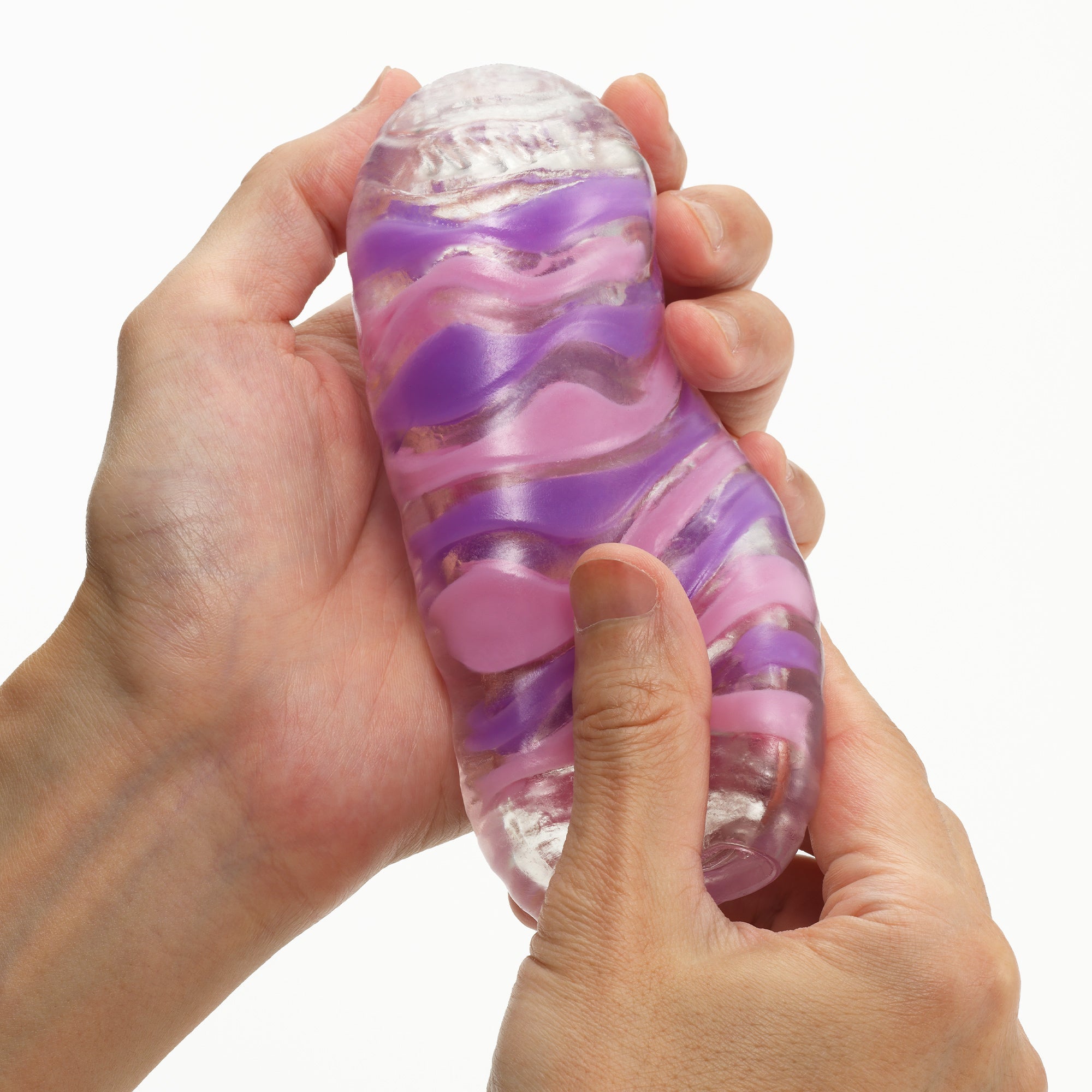 Two hands hold a clear elastomer masturbator with pink and purple wavy patterns.