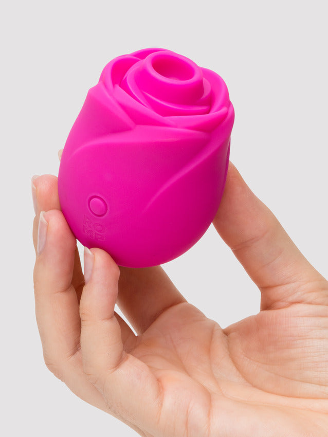 A pink rose-shaped clitoral stimulator held in a hand.