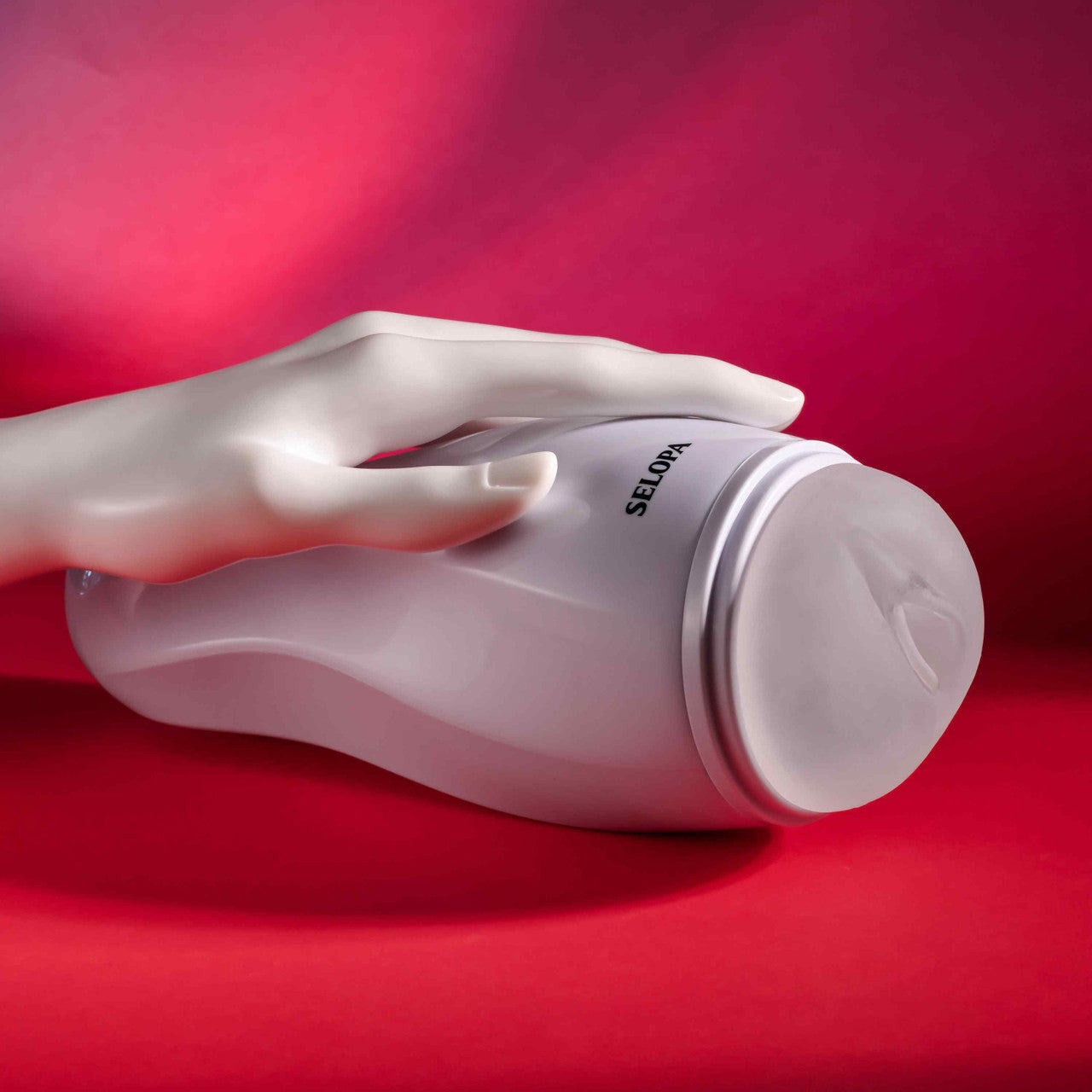 A white Selopa vibrating vaginal stroker held by a mannequin hand on a red background.