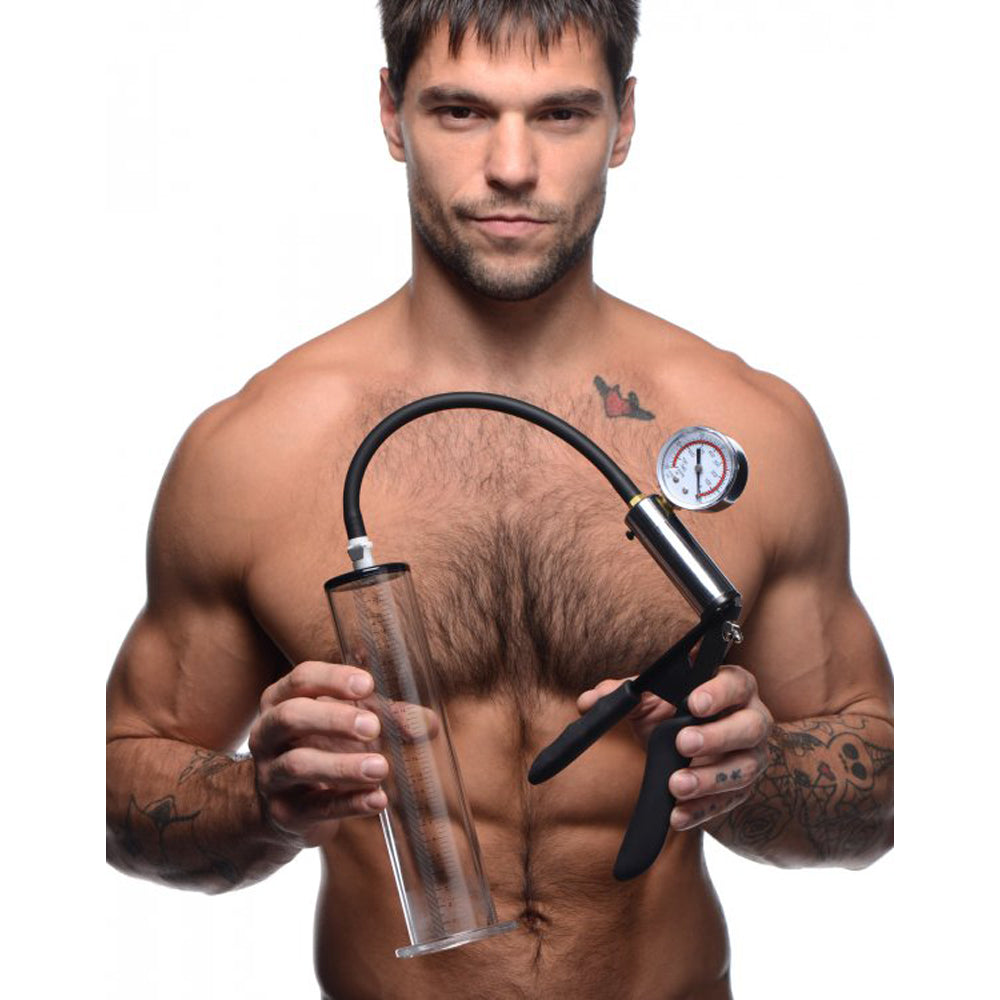 Man holding a penis pump with a clear cylinder and pressure gauge.
