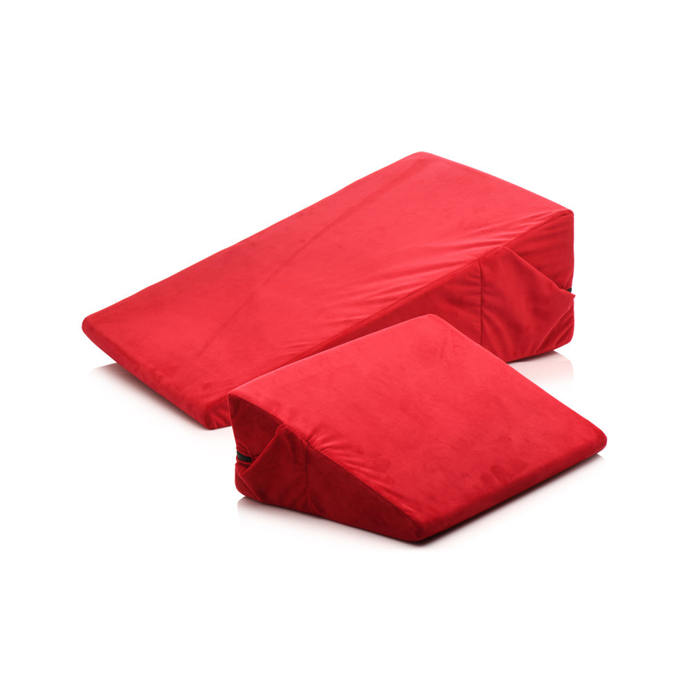 Two red velvet foam wedge pillows of different sizes.