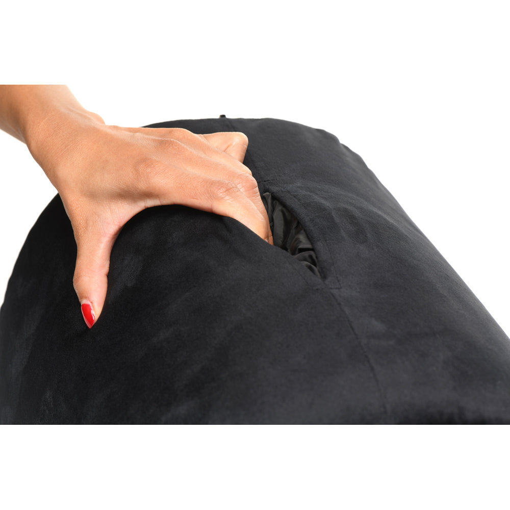 A hand reaches into the pocket of a black ergonomic sex toy saddle cushion.