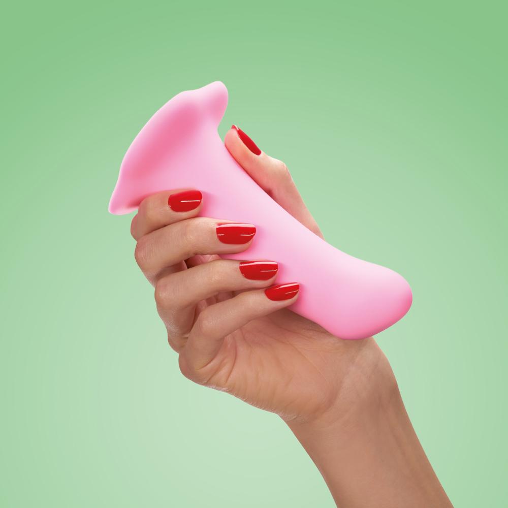 A pink curved dildo with a suction base held by a hand with red nail polish.