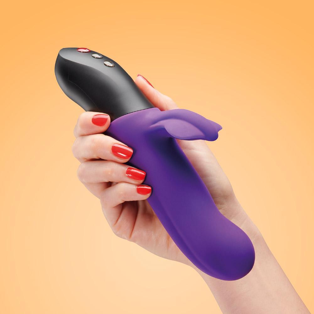 A purple rabbit vibrator with a black top is held in a hand.