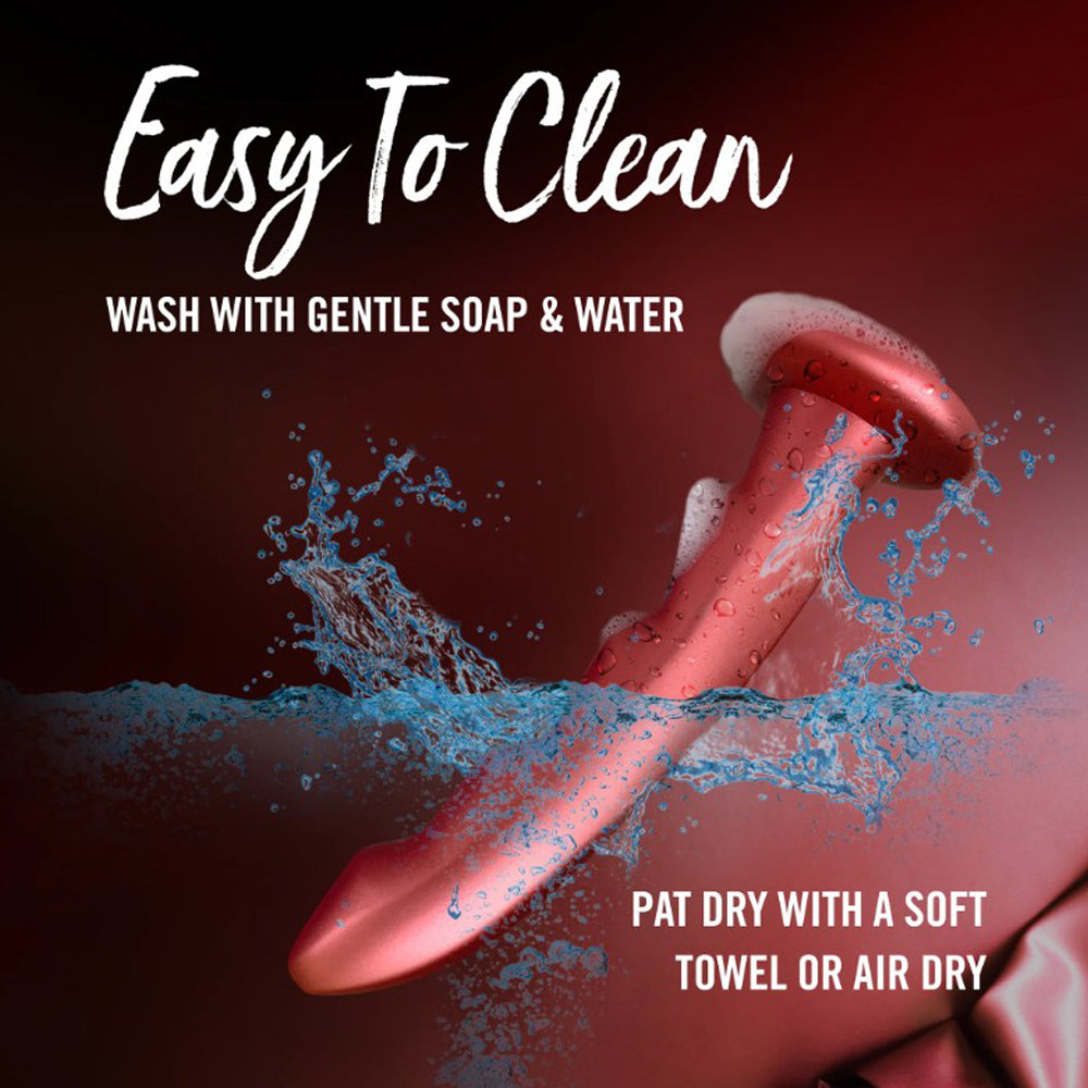 Red silicone G-spot dildo being washed with soap and water.