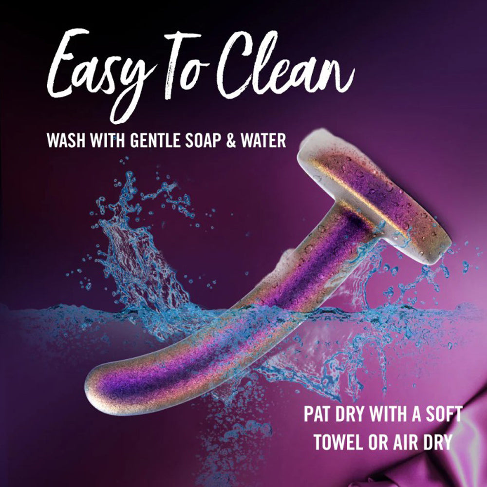 A curved, iridescent dildo being washed with water and soap.