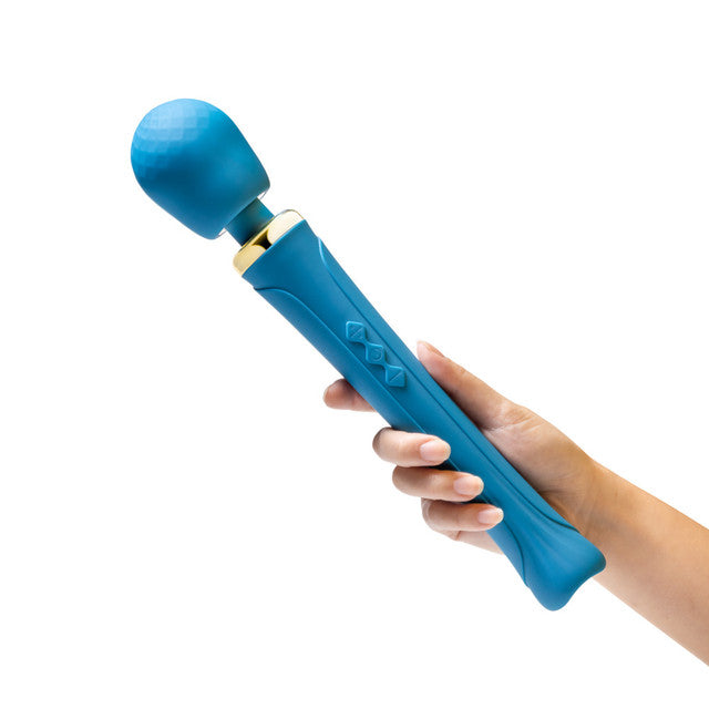 A blue wand massager with a textured head and gold accents is held in a hand.