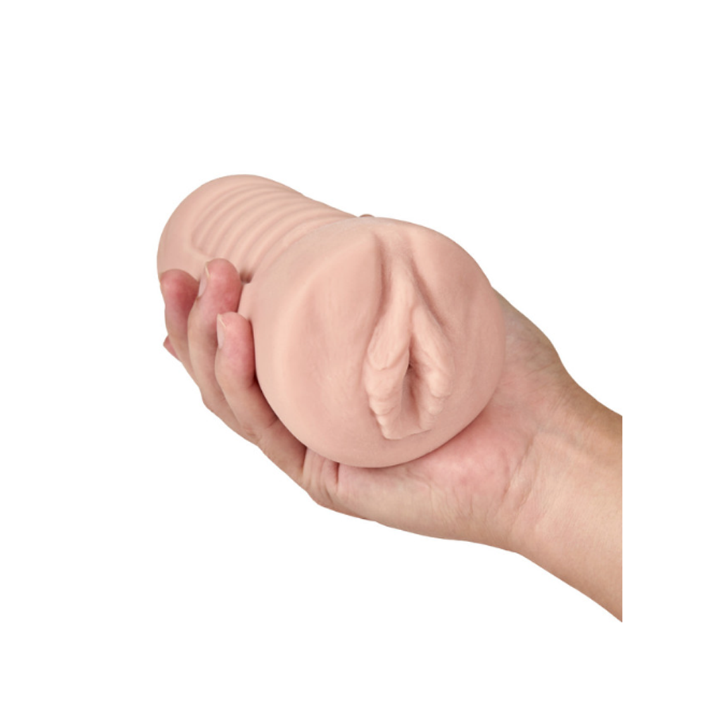 A hand holds a blush-colored textured stroker with a ribbed interior and a vulva-like opening.