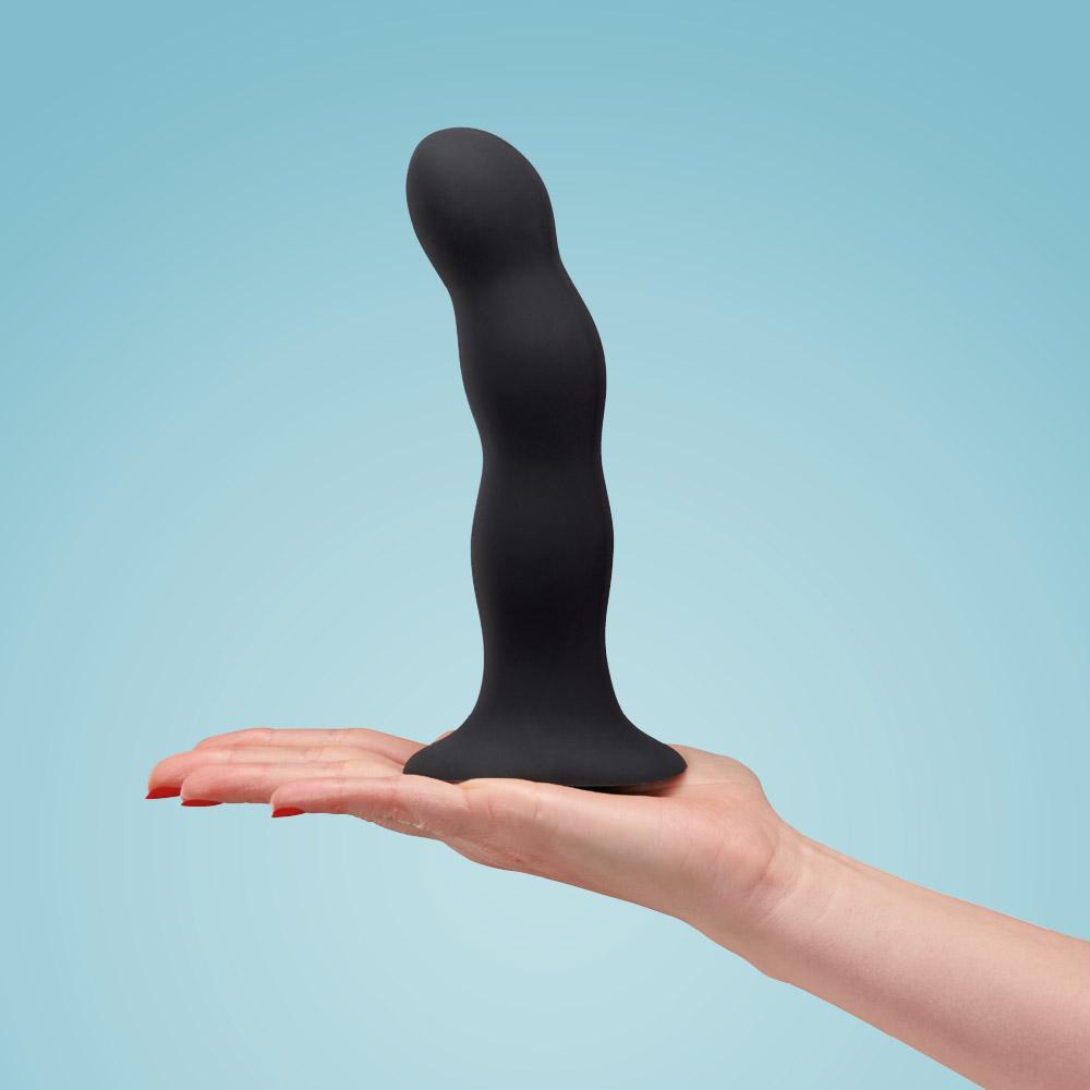 Black weighted internal motion dildo with a suction base held in a hand.