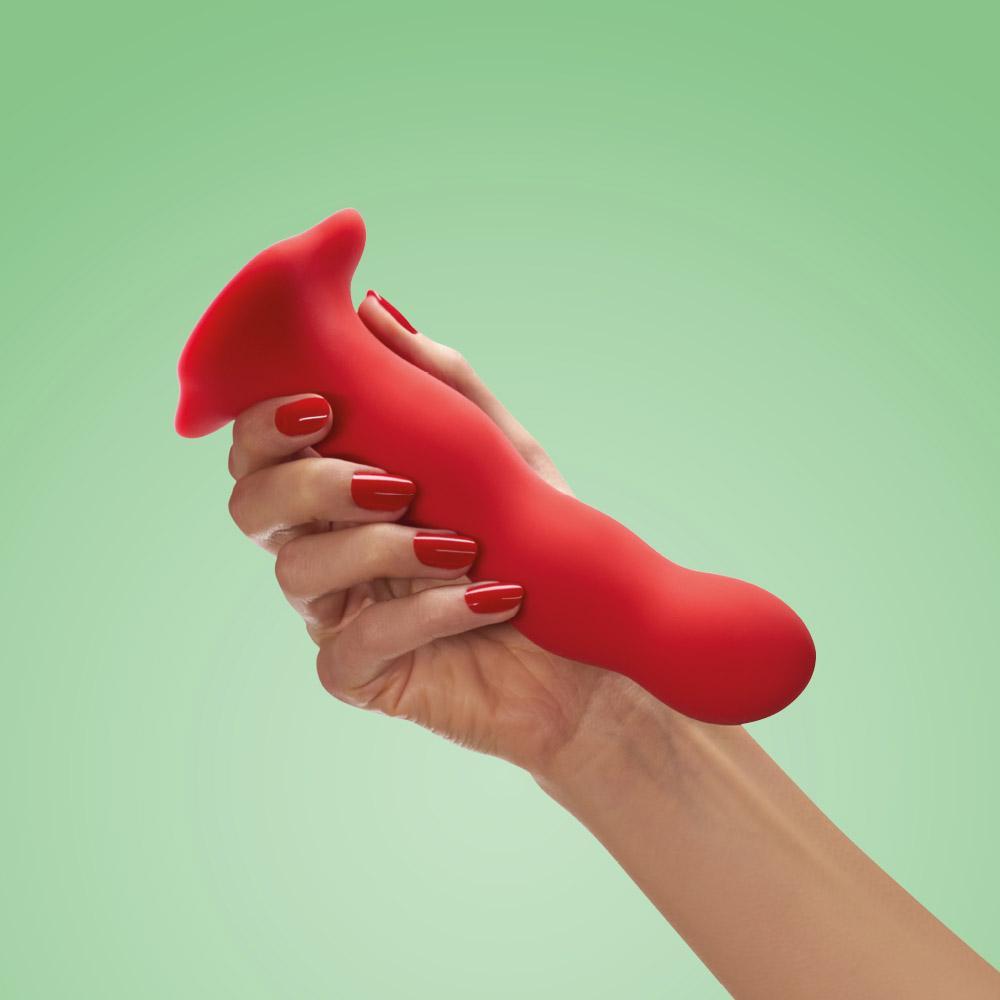 A red weighted internal motion dildo with a suction base held in a hand.