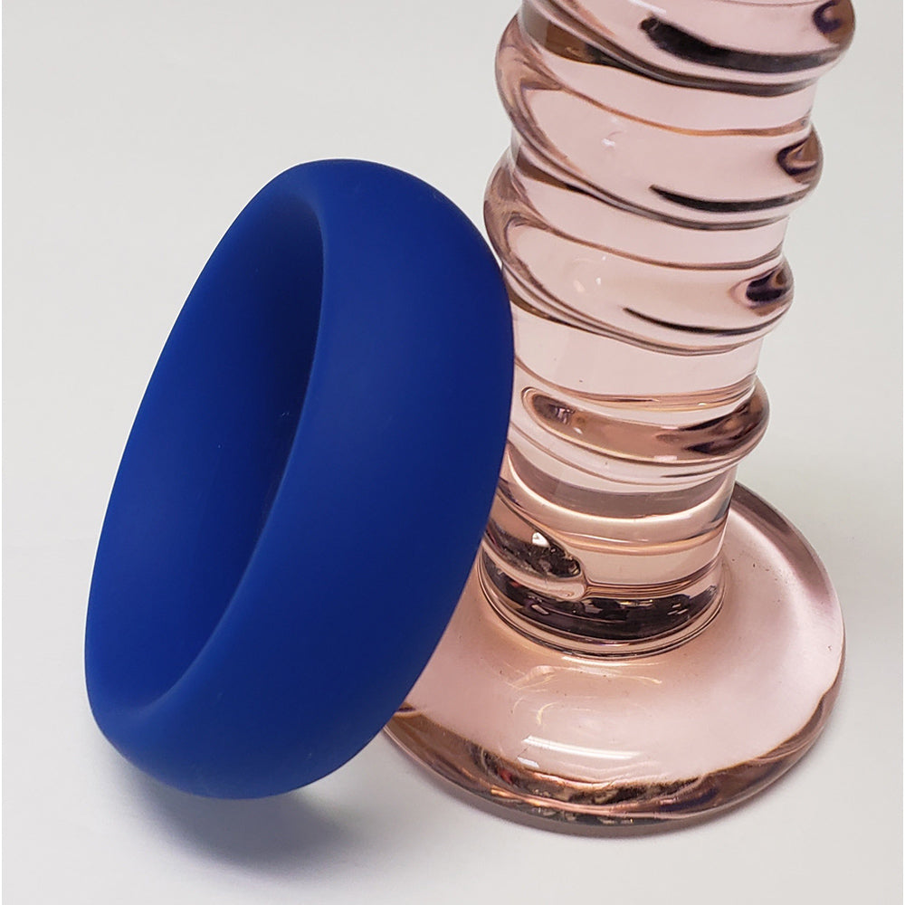 Blue silicone donut cock ring next to a pink glass object.