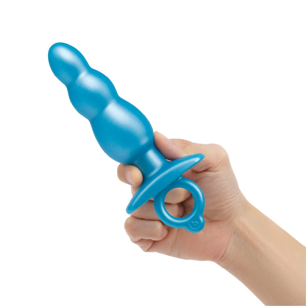 A blue beaded silicone anal plug with a retrieval ring held in a hand.