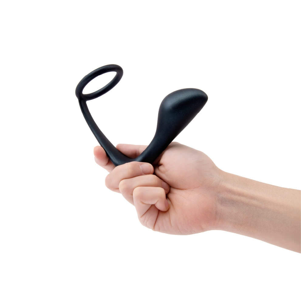 Black silicone dual stimulation cock ring and prostate plug held in a hand.