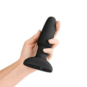 A black silicone rimming plug held in a hand.
