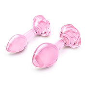 Two pink glass butt plugs with rose-shaped bases.