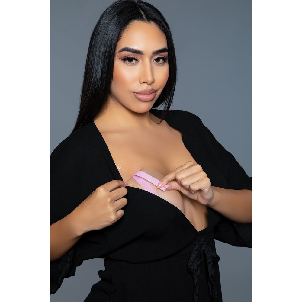 Clear adhesive breast lift tape roll being applied by a woman.