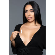 A woman applies a clear fashion strip to her chest.