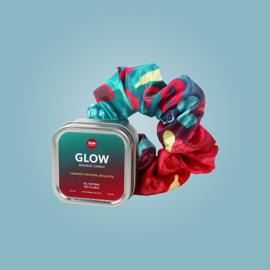 A massage candle in a tin with a colorful scrunchie.