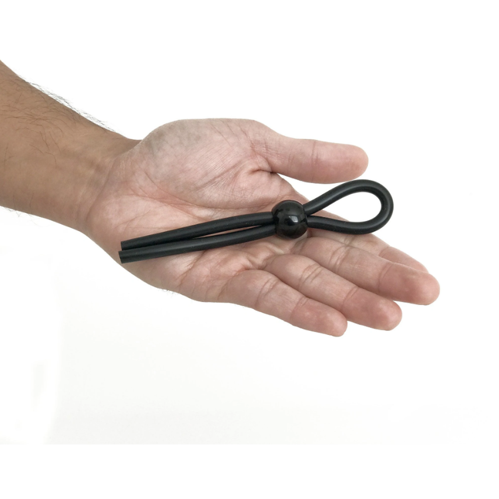 Adjustable black silicone cock ring leash with a bead on a hand.